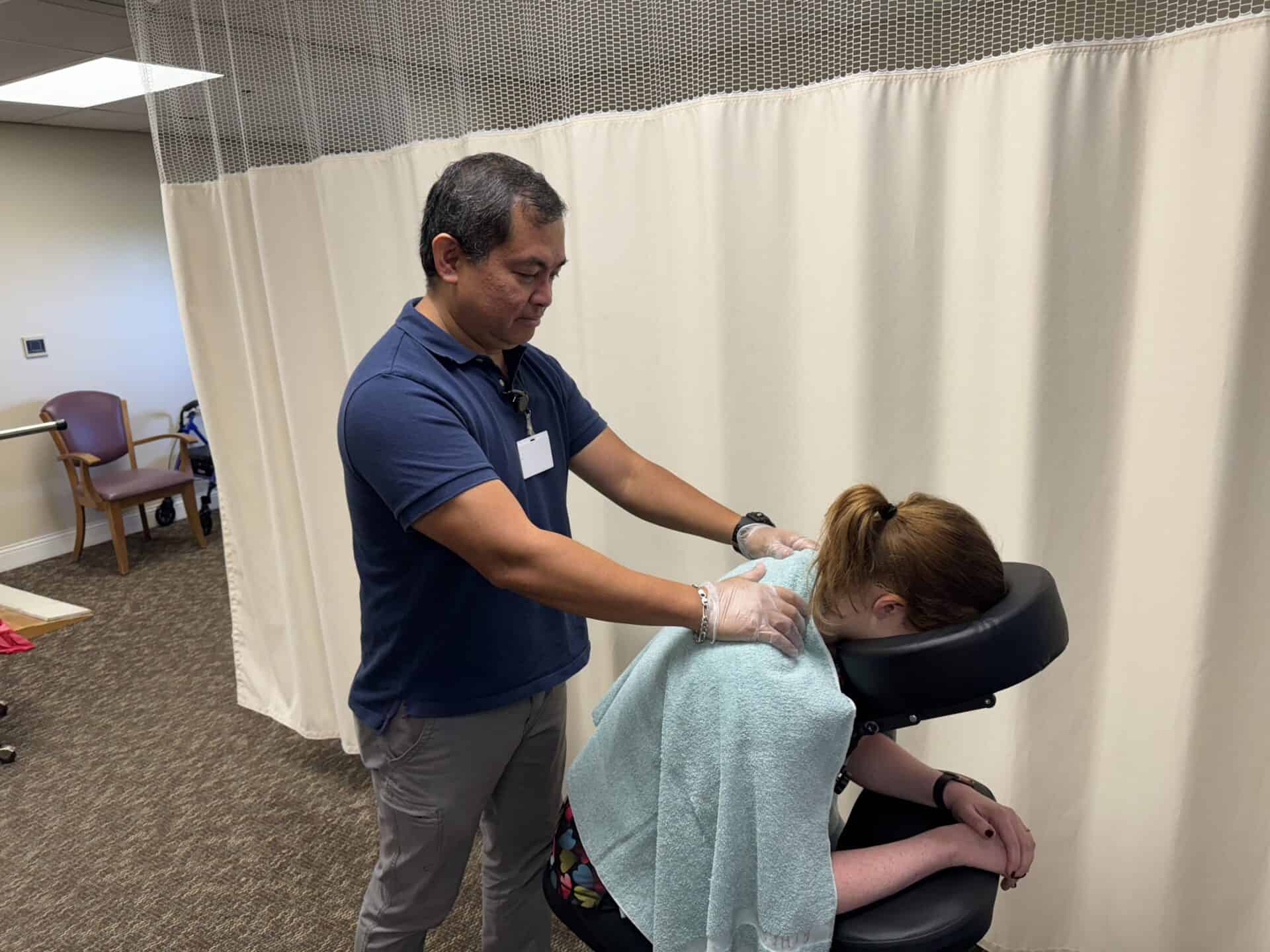 Therapist performing shoulder massage in clinic room