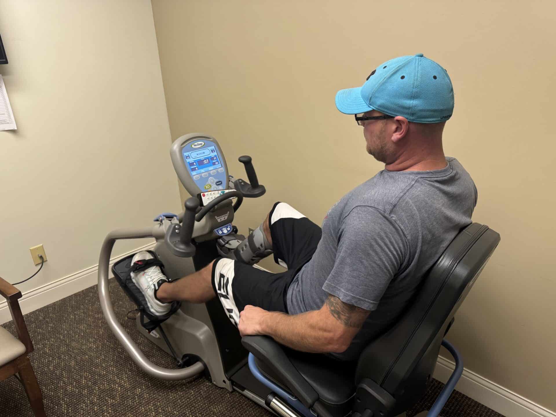 Man using recumbent exercise bike in clinic