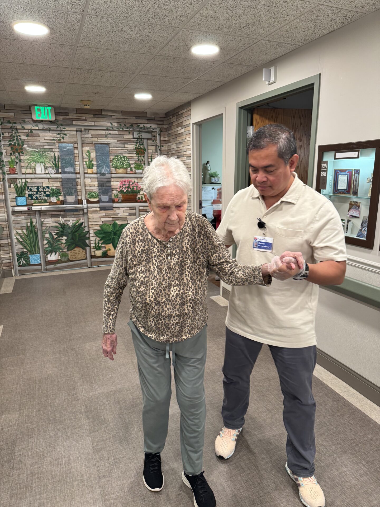 Elderly woman assisted by two people indoors